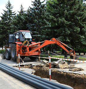 Excavator at construction site near trees.