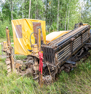 Yellow drilling machine in grassy area.
