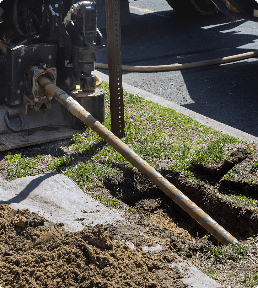 Machine drilling pipe into ground trench.