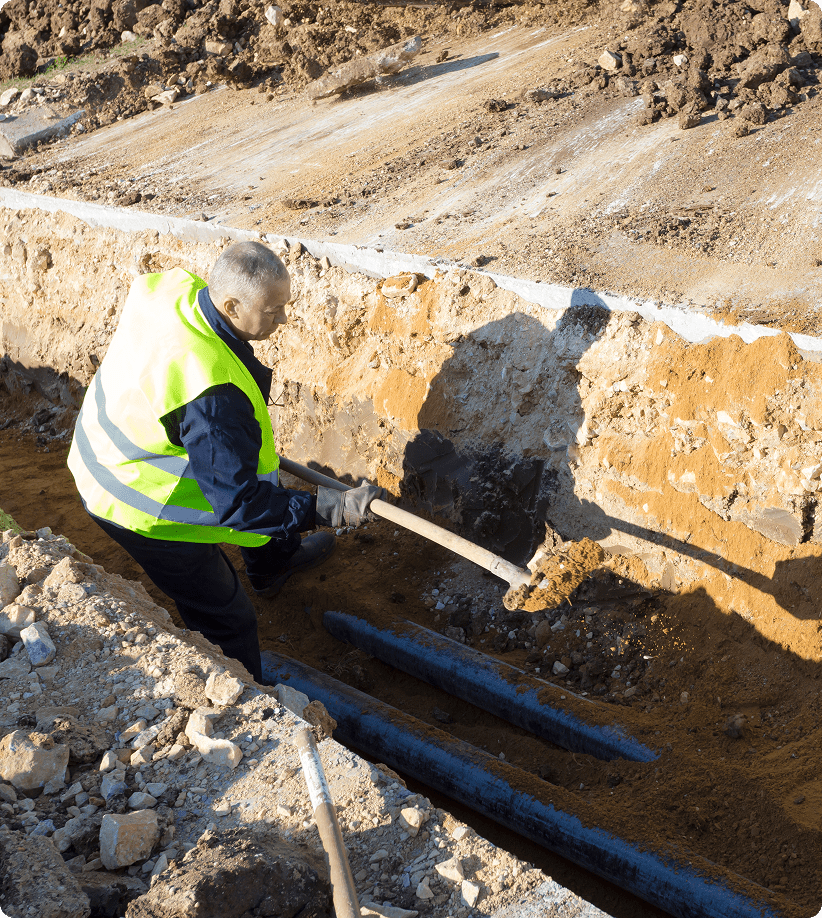 Worker digging trench with shovel.